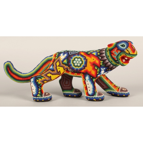 27 - A Mexican Huichol beaded jaguar figure, 35cm wide