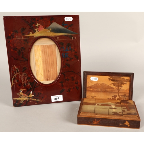 254 - Red lacquered Oriental-style picture frame and small inlaid wooden box with Mount Fuji design contai... 