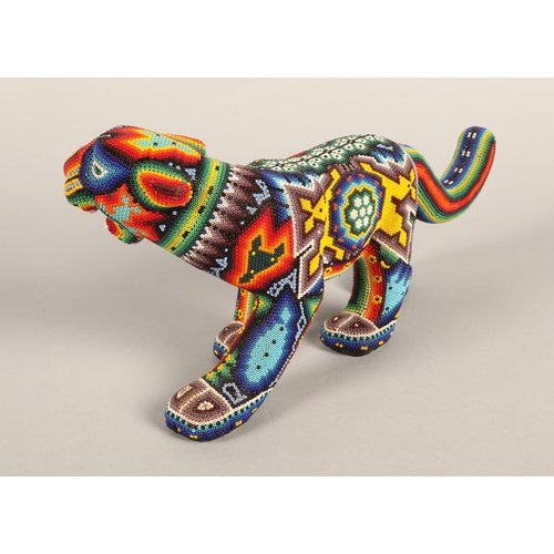 27 - A Mexican Huichol beaded jaguar figure, 35cm wide