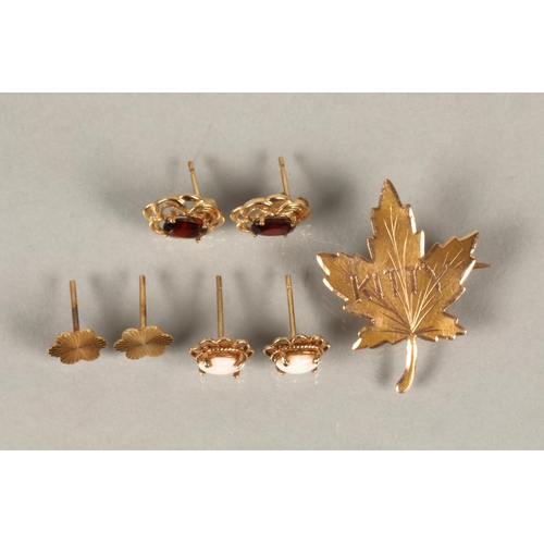 98 - A 10kt gold maple leaf brooch, a 9kt gold pair of stud earrings set with red gems, another pair ille... 