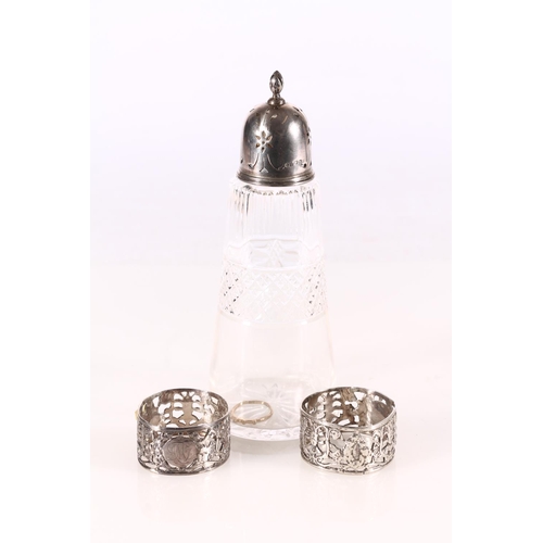 483 - Silver and cut glass sugar shaker, pair of silver openwork napkin rings and a plated ring.