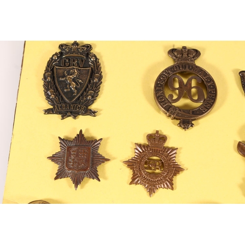 491 - Board of military cap badges and buttons to include 96th Regiment, 1st RDM (Royal Devon Military), S... 