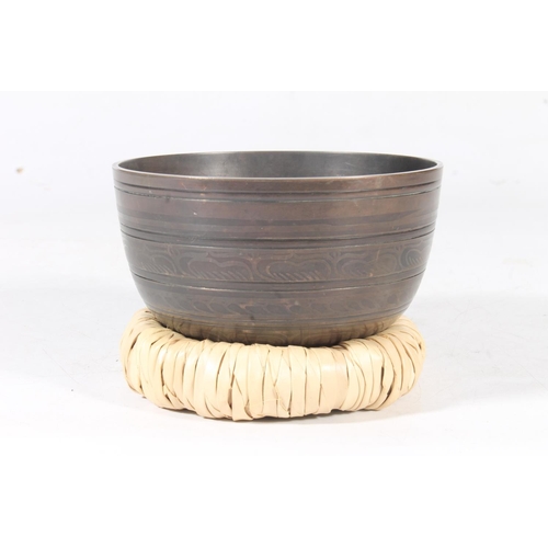 11 - Tibetan bronze singing bowl, with original rush wove base, 15cm.