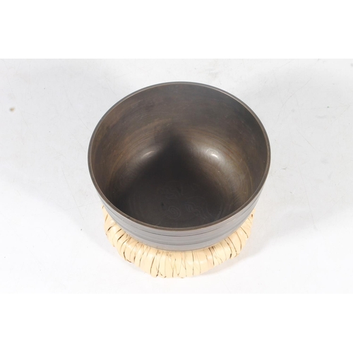 11 - Tibetan bronze singing bowl, with original rush wove base, 15cm.