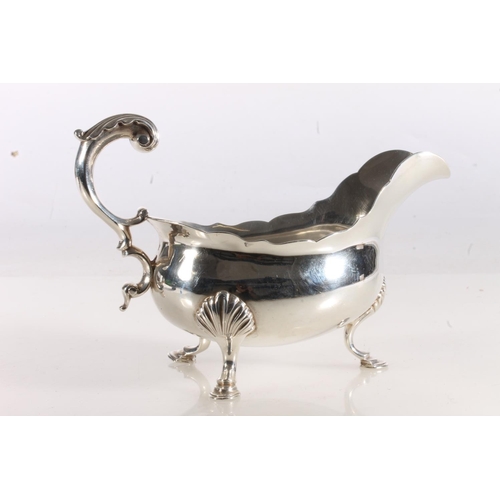 50 - George III silver sauce boat of typical form with serpentine edge, scroll handle, raised on three st... 