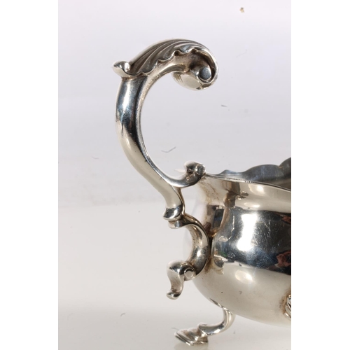 50 - George III silver sauce boat of typical form with serpentine edge, scroll handle, raised on three st... 