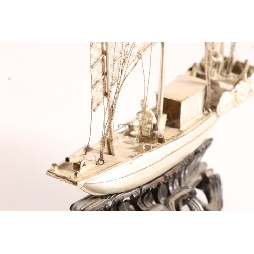 125 - Oriental white metal model of a triple masted sailing boat or junk, raised on carved wooden stand, 6... 