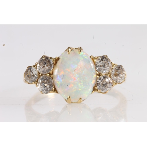 178 - Unmarked yellow metal opal and diamond seven stone ring, the large oval opal flanked by trios of 0.1... 