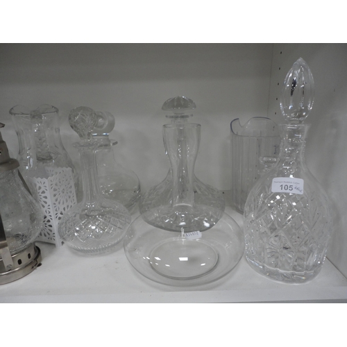 105 - Shelf lot of glass to include crystal decanters with stoppers, glass jugs and vases.