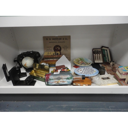 106 - Shelf lot of sundries to include ship in a bottle, telephone, playing cards, books, bookends etc