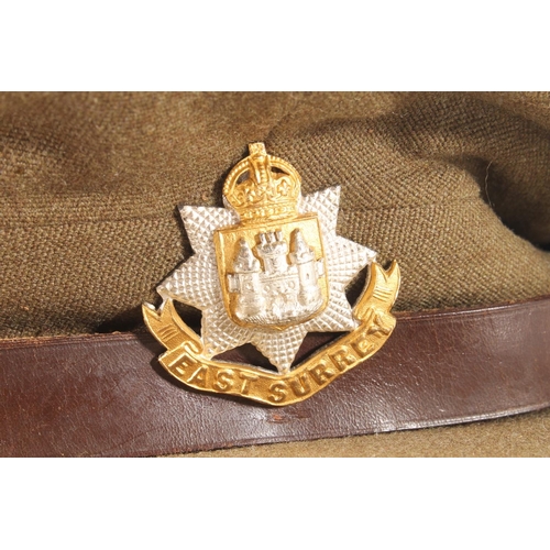 1761 - Unhallmarked diecast white metal and gilt metal East Surrey Regiment cap badge on a khaki green peak... 