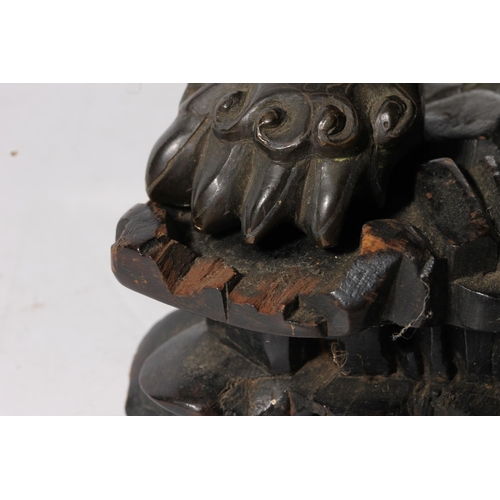 486 - Chinese cast bronze temple dog modelled resting paw on orb, raised on carved wood base, 26cm tall.