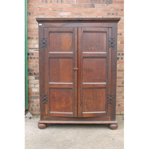 561 - Antique oak two door cupboard or wardrobe, raised on bun feet, 124cm wide.