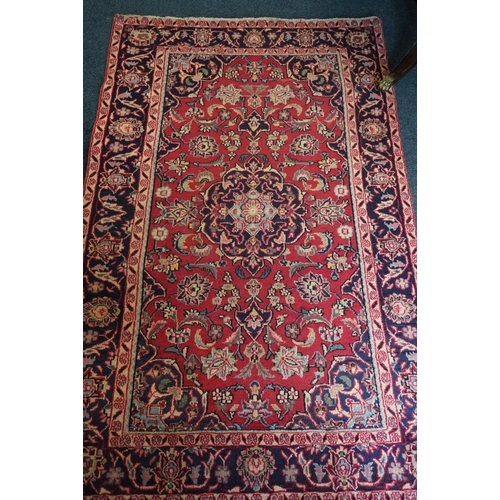 594 - Red ground Persian Keshan rug, the central field surrounded by blue ground border. 195cm x 123cm.