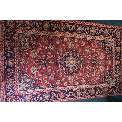 594 - Red ground Persian Keshan rug, the central field surrounded by blue ground border. 195cm x 123cm.