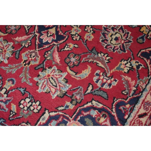 594 - Red ground Persian Keshan rug, the central field surrounded by blue ground border. 195cm x 123cm.