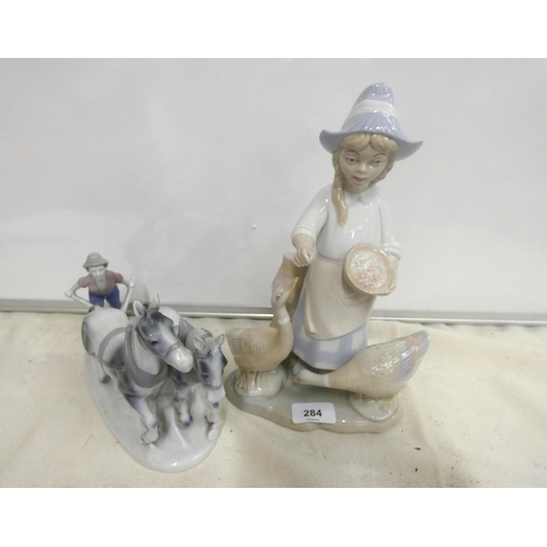 284 - Two Continental figures including Bavarian man ploughing, and a girl feeding ducks. 28cm high