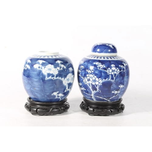 109 - Two Chinese blue and white porcelain ginger jars decorated with prunus blossom and raised on wooden ... 