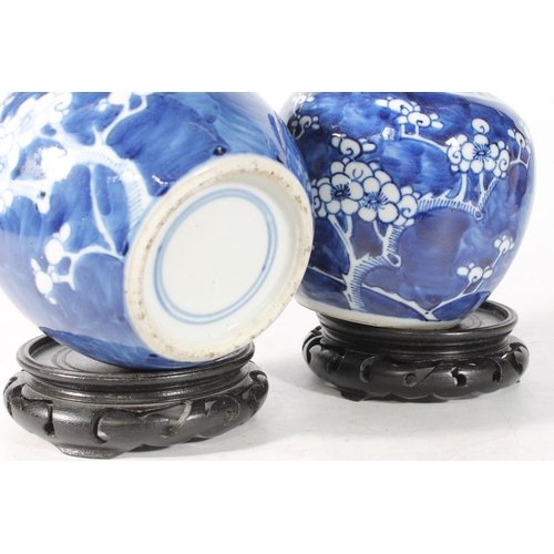 109 - Two Chinese blue and white porcelain ginger jars decorated with prunus blossom and raised on wooden ... 