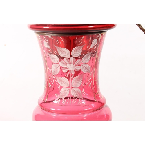 27 - Cranberry glass oil lamp decorated with white enamel flowers.