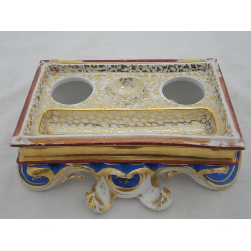 205 - Continental ceramic desk stand with winged putti surmount and integral inkwells, decorated with encr... 