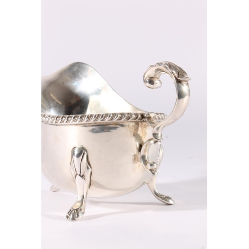 21 - George V silver sauce boat of plain form with reeded edge and raised on three shell headed paw feet ... 