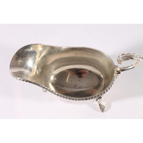 21 - George V silver sauce boat of plain form with reeded edge and raised on three shell headed paw feet ... 