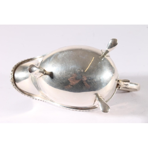 21 - George V silver sauce boat of plain form with reeded edge and raised on three shell headed paw feet ... 