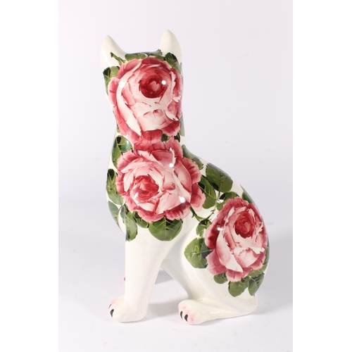 456 - Wemyss Ware pottery cat, in seated position and decorated with cabbage roses with inset green glass ... 