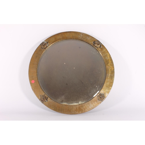 620 - Early 20th century Arts and Crafts style round mirror, the round planished brass frame with stylised... 