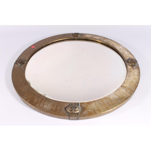 620 - Early 20th century Arts and Crafts style round mirror, the round planished brass frame with stylised... 