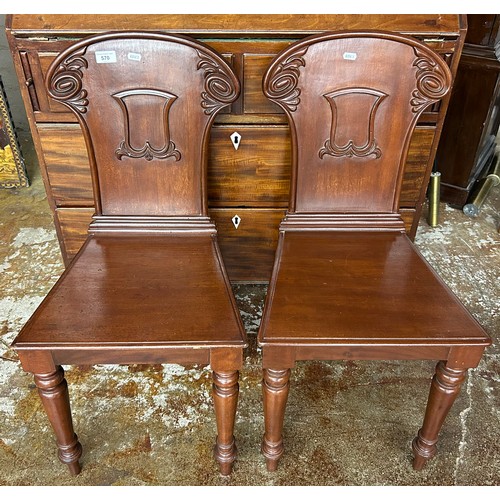 570 - Pair carved mahogany hall chairs, raised on fluted supports