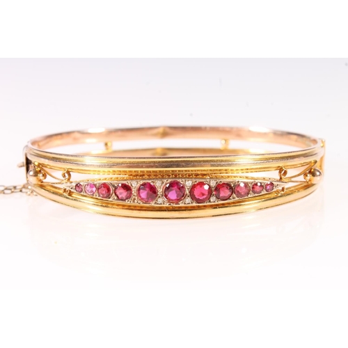 175 - Antique style 9ct gold bangle set with eleven graduated ruby red stones, 7.9g gross.