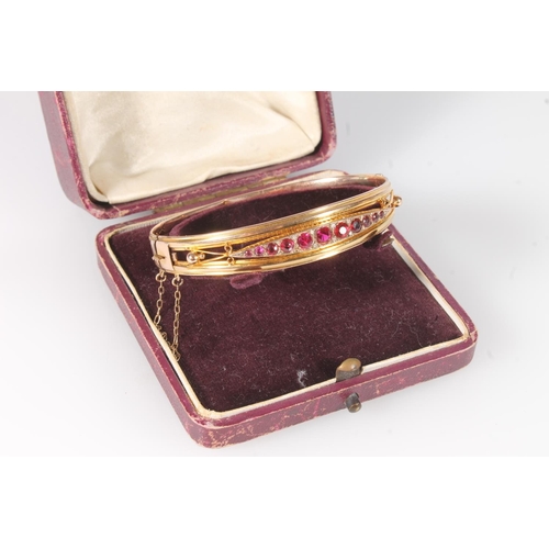 175 - Antique style 9ct gold bangle set with eleven graduated ruby red stones, 7.9g gross.