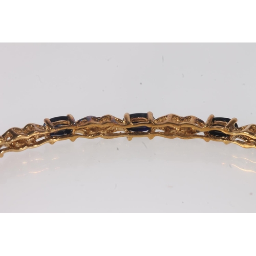 184 - Unmarked yellow metal sapphire and diamond bangle, the clasp stamped 'DIA', 7g gross.