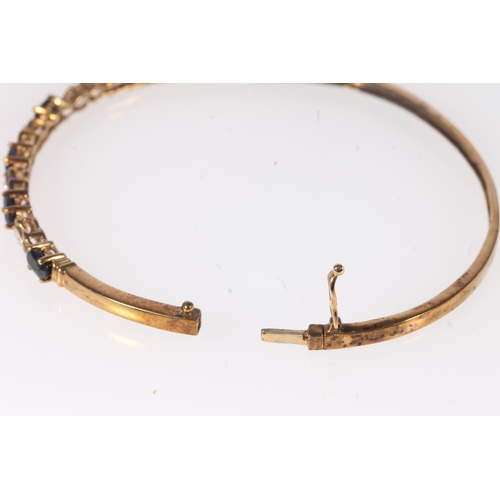 184 - Unmarked yellow metal sapphire and diamond bangle, the clasp stamped 'DIA', 7g gross.