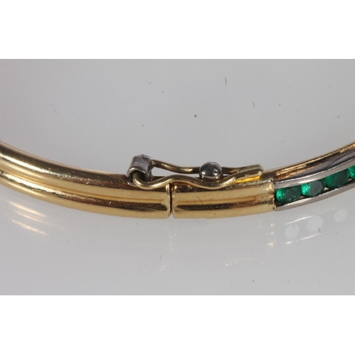 218 - Unmarked yellow gold bangle, on hinged clasp, the face interspersed with channel set round emeralds,... 