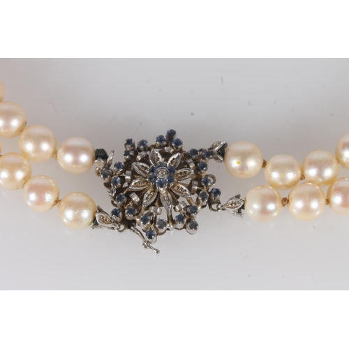 224 - Two strand pearl bead necklace on a 18ct white gold star form clasp set with small diamond and blue ... 