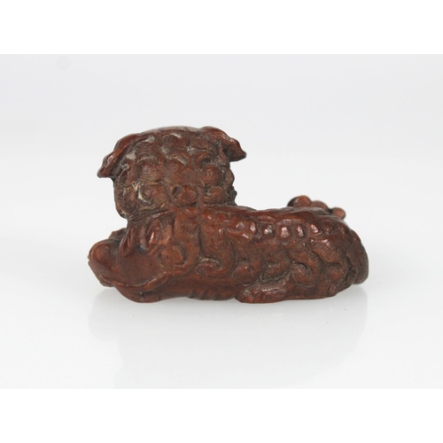 553 - Late 19th century carved wooden netsuke of a recumbent lion dog holding a ball, unsigned, 5cm.