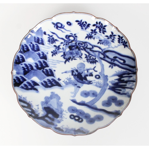 576 - 18th century Japanese Arita blue and white dish decorated with a figure in a landscape beneath a flo... 