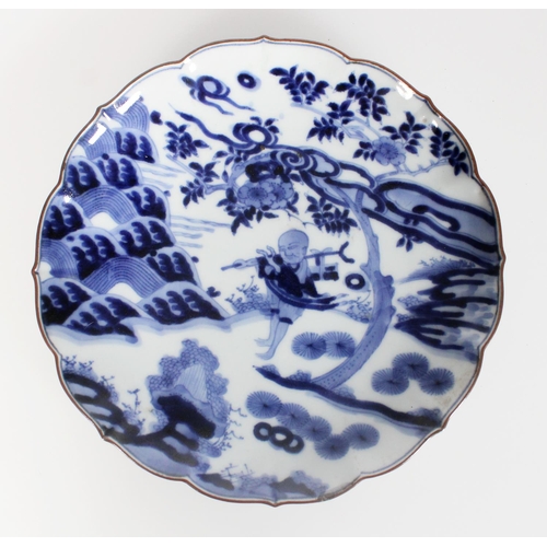 576 - 18th century Japanese Arita blue and white dish decorated with a figure in a landscape beneath a flo... 