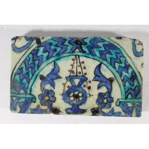 495 - Iznik glazed pottery half tile, 22cm long, another tile with Fleur di Lis design, held in wooden fra... 