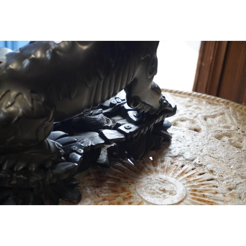 523 - Chinese cast bronze temple dog modelled resting paw on orb, raised on carved wood base, 26cm tall.Do... 