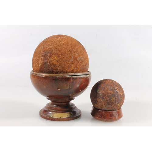 1451 - Cast iron cannonball, approximately 10cm diameter raised on turned wooden cup stand bearing brass pl... 