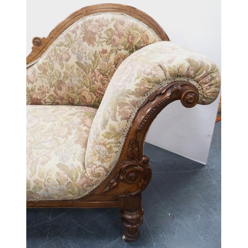 110 - Late Victorian walnut scroll-back chaise longue, upholstered in later floral fabric, carved with app... 