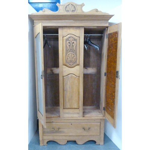 189 - Early 20th century pine two-door wardrobe decorated with carved fleur-de-lys motifs, with shaped cor... 