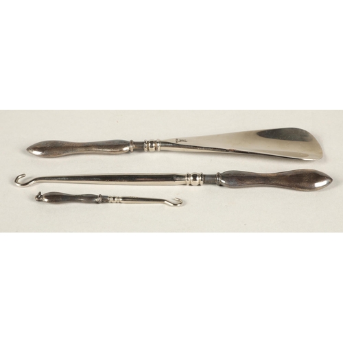 263 - Silver handled shoe horn and two button hooks, cased.