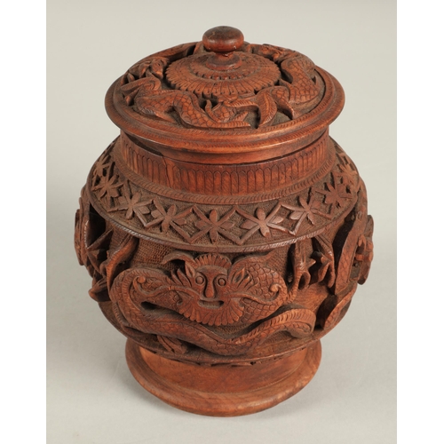 269 - Carved eastern wooden jar and cover decorated with dragons. 28cm