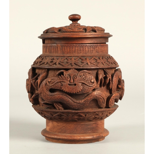 269 - Carved eastern wooden jar and cover decorated with dragons. 28cm