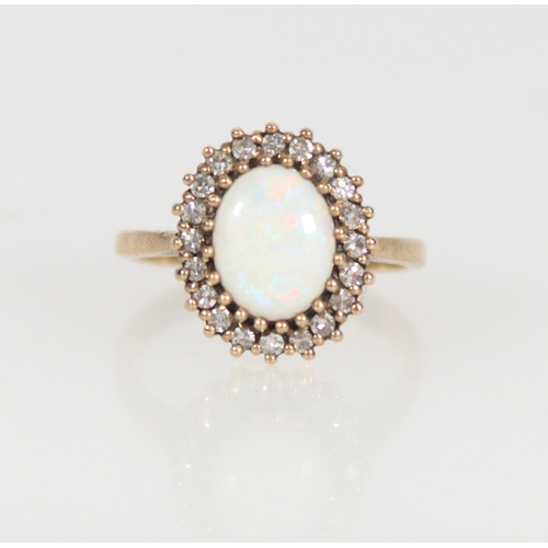 558 - 9ct gold and opal cluster ring, the oval opal wihin a halo of small white stones, size L/M, 2.9g.